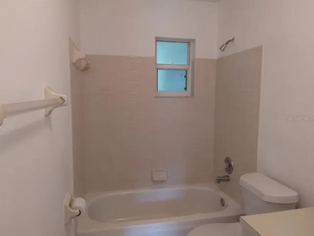 a white bath tub sitting next to a white toilet and a shower