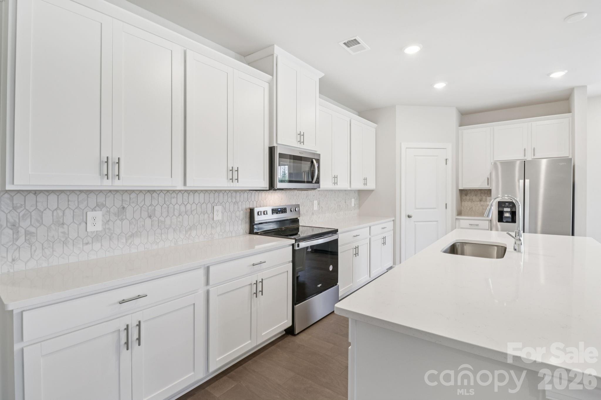 2449 Chartwell Street Stanley, NC 28164 - Photo 20 of 23 a kitchen with white cabinets and stainless steel appliances