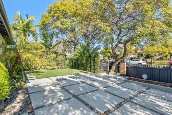 a big yard with large trees and wooden fence