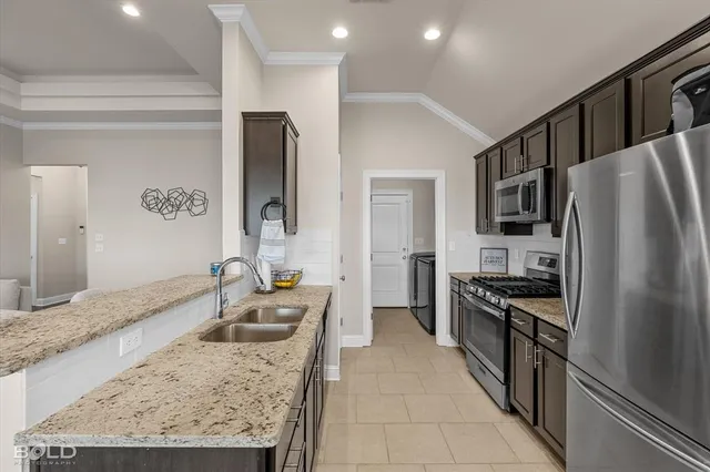 a utility room with stainless steel appliances granite countertop a sink stove and refrigerator