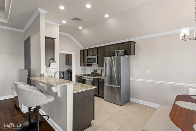 a kitchen with granite countertop stainless steel appliances a refrigerator stove top oven and sink