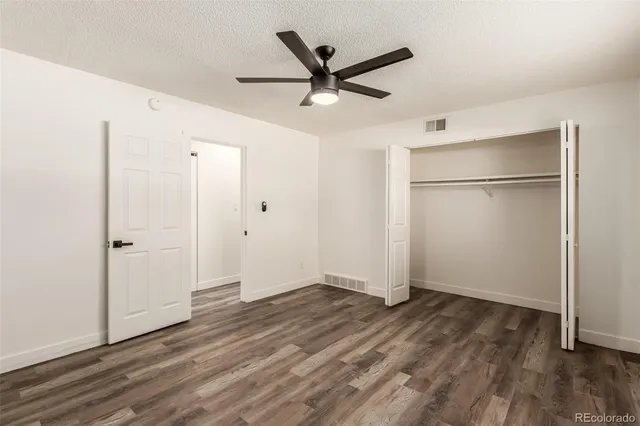 a view of empty room with wooden floor and ceiling fan