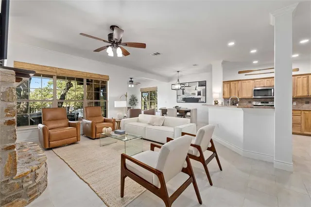 a living room with furniture and a large window with kitchen view