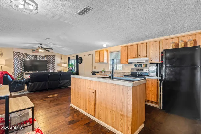 a kitchen with stainless steel appliances granite countertop a refrigerator a stove a sink dishwasher and a refrigerator with wooden floor