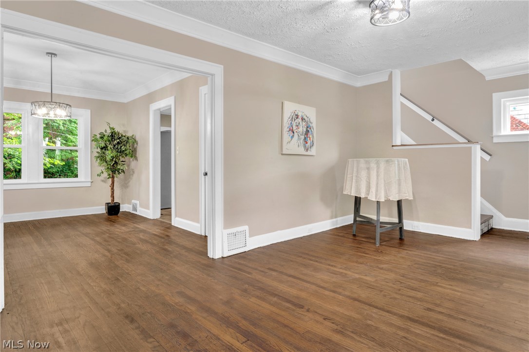 3218 Tullamore Road Cleveland, OH 44118 - Photo 4 of 42 Unfurnished room with an inviting chandelier, a textured ceiling, dark hardwood / wood-style floors, and crown molding