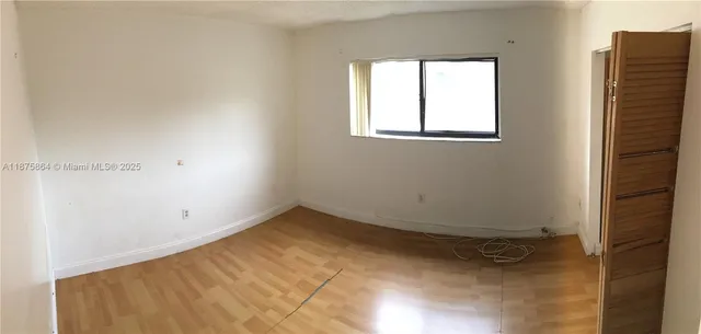 a view of a hallway with wooden floor and a bathroom