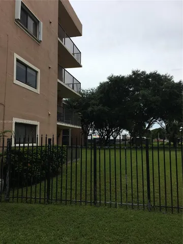 a view of a house with a big yard plants and large trees