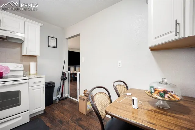 a kitchen with sink a stove and white cabinets with wooden floor