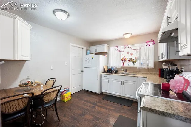 a kitchen with granite countertop a dining table chairs stove refrigerator and sink