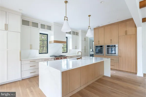 a large kitchen with kitchen island a large counter top a sink a stove and wooden floors