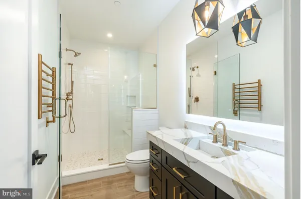 a bathroom with a granite countertop sink a toilet and shower