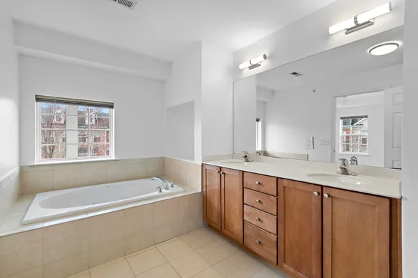 a spacious bathroom with a granite countertop tub sink shower and mirror