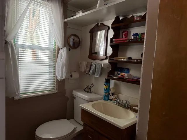 a bathroom with a sink a toilet and a window