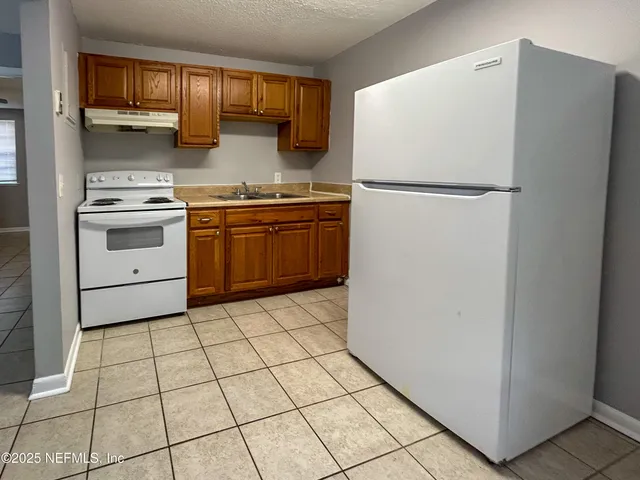 a kitchen with a stove a refrigerator and a white cabinets