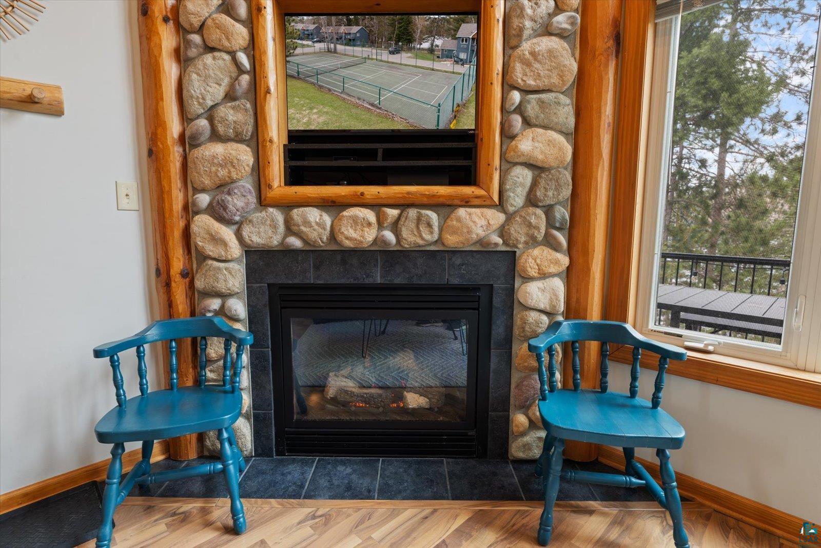 6266 Giants Ridge Road Biwabik, MN 55705 - Photo 12 of 37 Stone-clad fireplace with wood log surround, black hearth, and glass-front insert