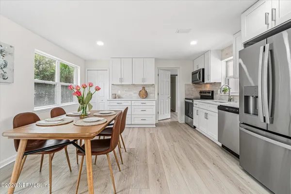 a kitchen with stainless steel appliances kitchen island granite countertop a dining table chairs and refrigerator