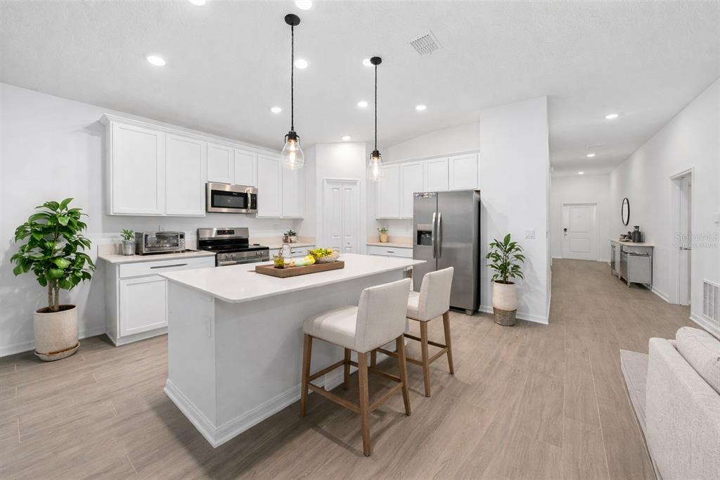 3977 Willowbrook Drive Edgewater, FL 32141 - Photo 4 of 22 a kitchen with kitchen island a refrigerator a stove a oven a sink a dining table and chairs with wooden floor