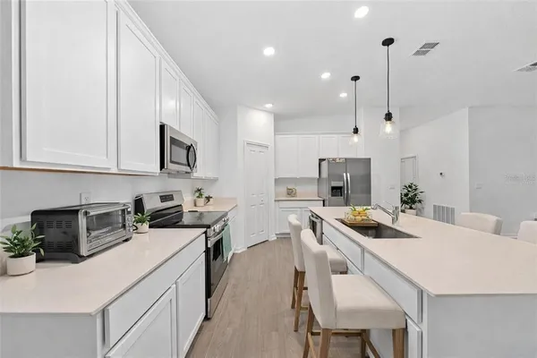 a kitchen with a sink a stove a refrigerator and chairs