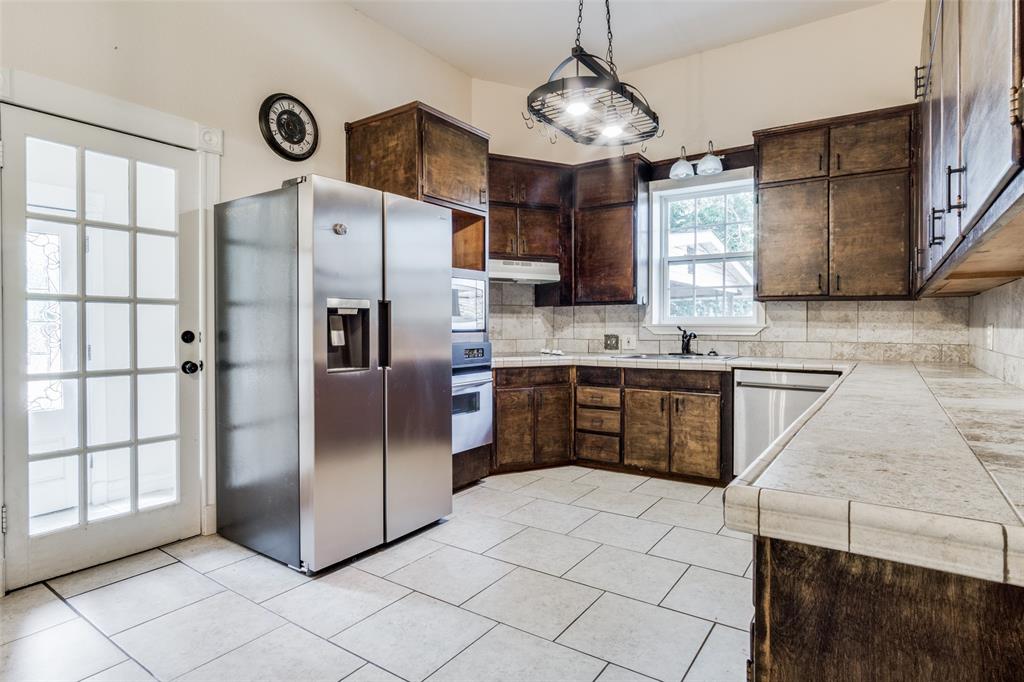1211 Cherokee Street Weatherford, TX 76086 - Photo 9 of 29 a kitchen with stainless steel appliances granite countertop a refrigerator a sink dishwasher a stove with wooden cabinets and floor