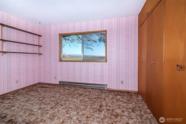 an empty room with painting on the wall and a window