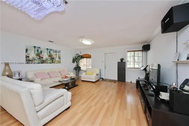 a living room with furniture a flat screen tv and a wooden floor