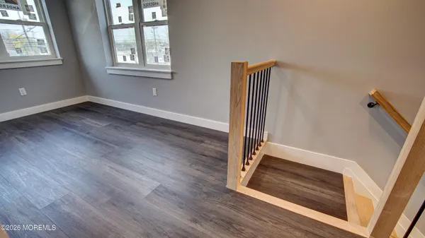 an empty room with wooden floor cabinet and windows