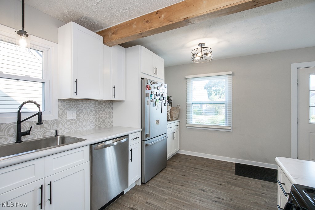 5607 Ridgewood Avenue Parma, OH 44129 - Photo 10 of 23 Kitchen featuring beam ceiling, dark hardwood / wood-style flooring, hanging light fixtures, appliances with stainless steel finishes, and sink