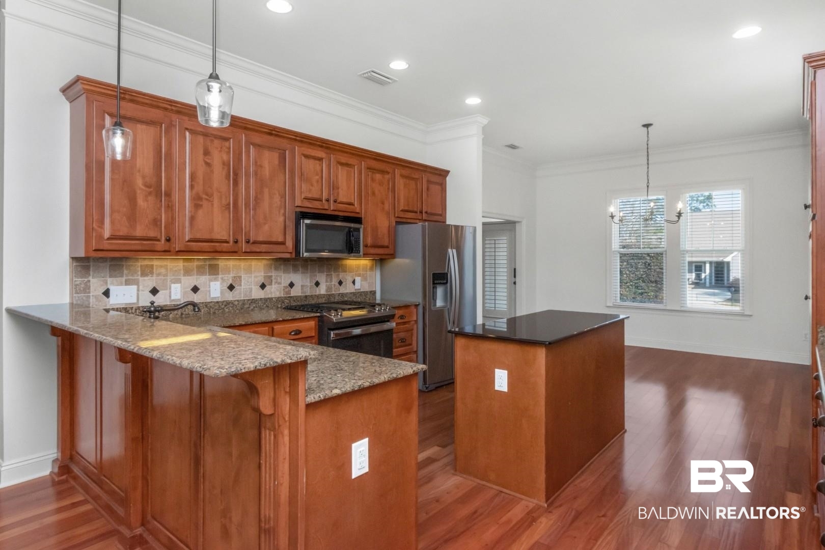 30585 Pine Court Daphne, AL 36527 - Photo 6 of 49 Kitchen featuring pendant lighting, brown cabinets, a kitchen island, dark stone counters, and stainless steel appliances