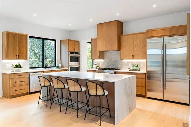 a kitchen with stainless steel appliances granite countertop a stove a sink a refrigerator and island