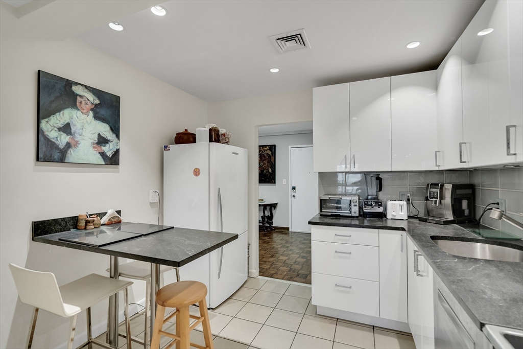 405 Langley Road, Unit 6 Newton, MA 02459 - Photo 24 of 42 a kitchen with stainless steel appliances granite countertop a stove a refrigerator a sink a dining table and chairs with wooden floor