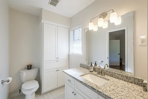 a bathroom with a granite countertop sink mirror vanity and toilet