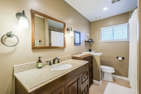a bathroom with a granite countertop sink a toilet and a mirror
