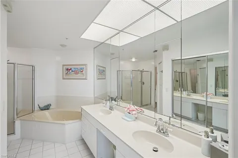 a bathroom with a double vanity sink mirror double and bathtub