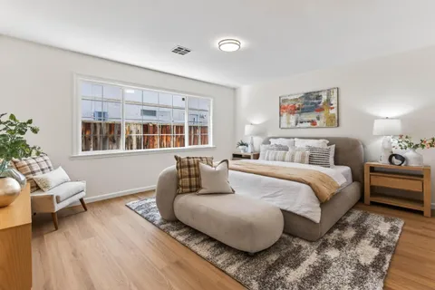 a spacious bedroom with a bed a couch and potted plant with the wooden floor