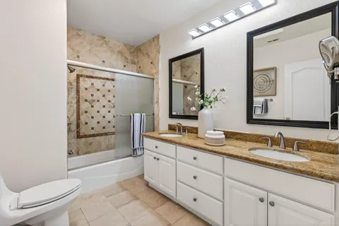 a spacious bathroom with a granite countertop sink toilet mirror and shower