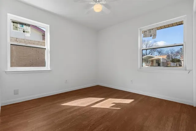 a view of empty room with wooden floor and fan
