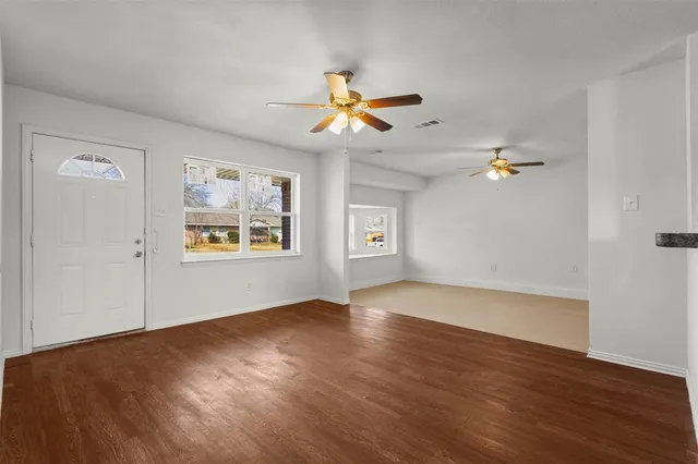 a view of empty room with wooden floor and fan