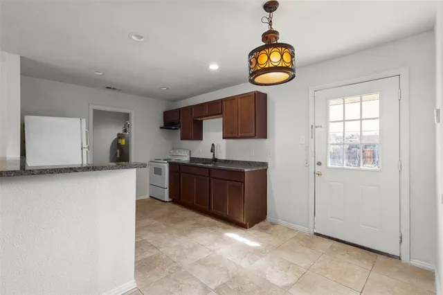 a kitchen with stainless steel appliances granite countertop a sink a stove top oven a counter space and cabinets