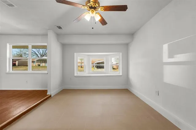 an empty room with windows and fan