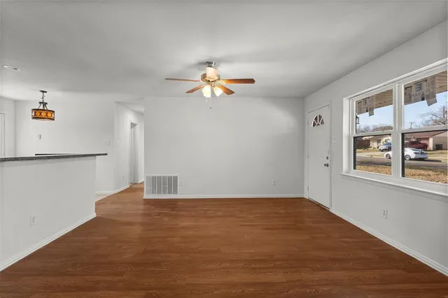 a view of a room with wooden floor and a ceiling fan