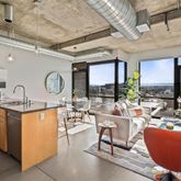 a living room with furniture a large window and stainless steel appliances
