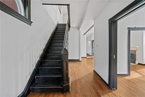 a view of an empty room with wooden floor and a ceiling fan