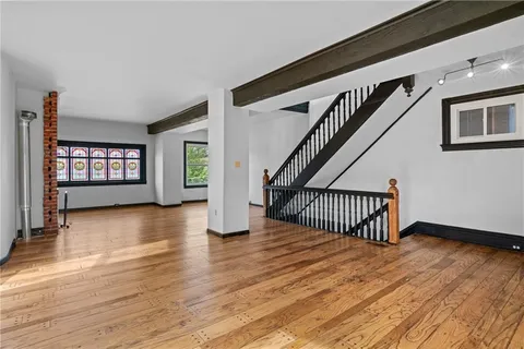 an empty room with wooden floor fireplace and windows