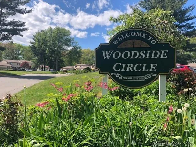 a sign of golf club on a wall under a tree