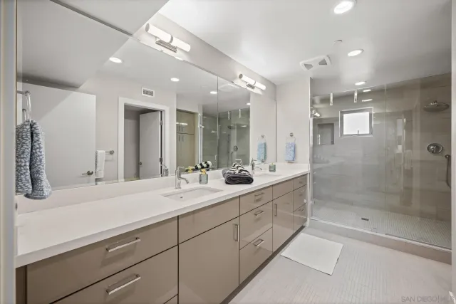 a spacious bathroom with a mirror a shower and vanity