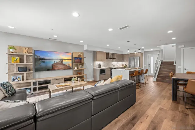 a living room with stainless steel appliances furniture and a kitchen view