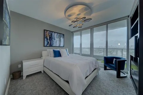 a spacious bedroom with a bed painting on wall and a large window