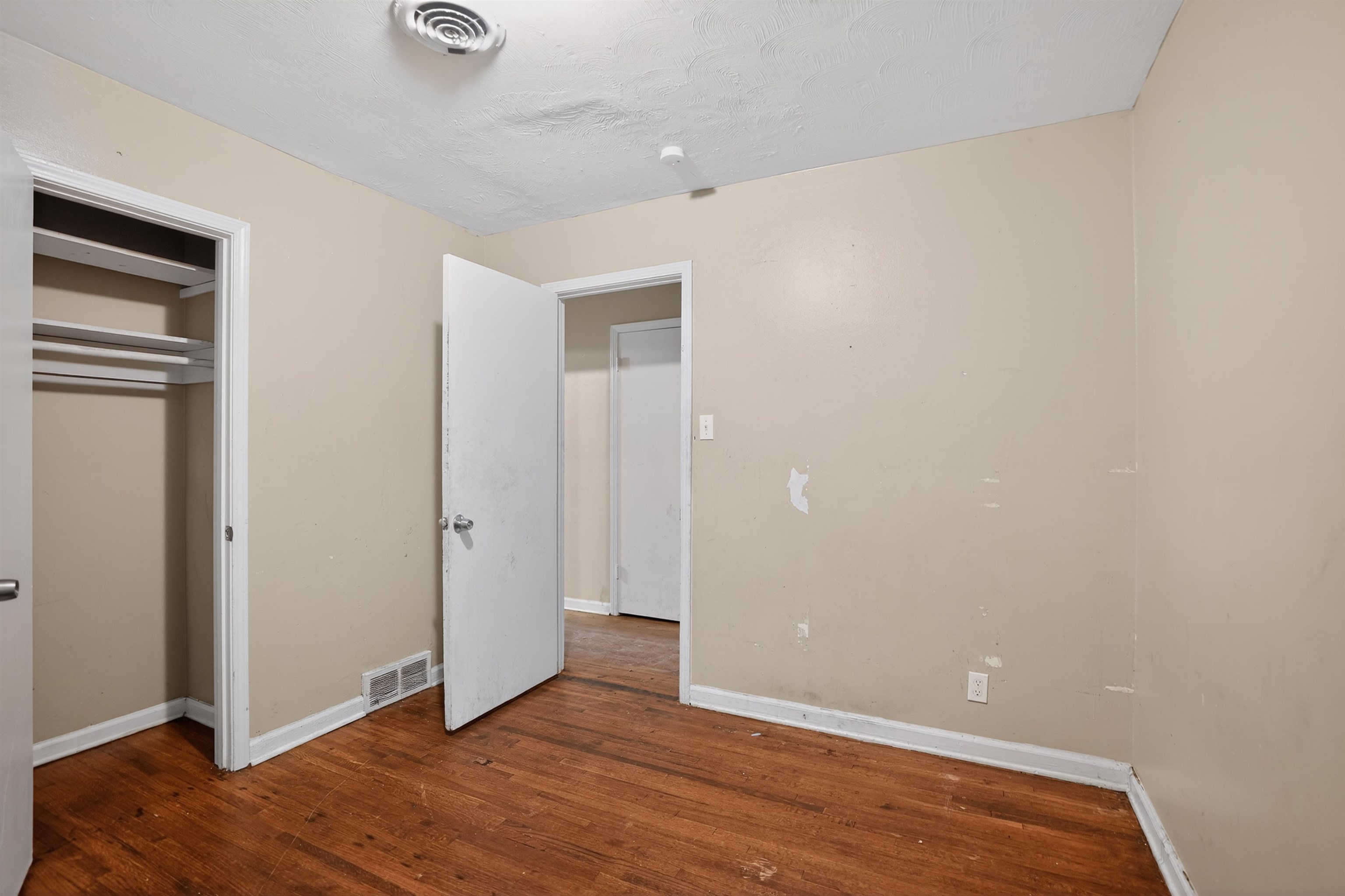 1890 Pennel Road Memphis, TN 38116 - Photo 21 of 25 Room featuring wood-finish flooring, neutral wall tones, white trim, and a built-in closet with shelving and hanging rods