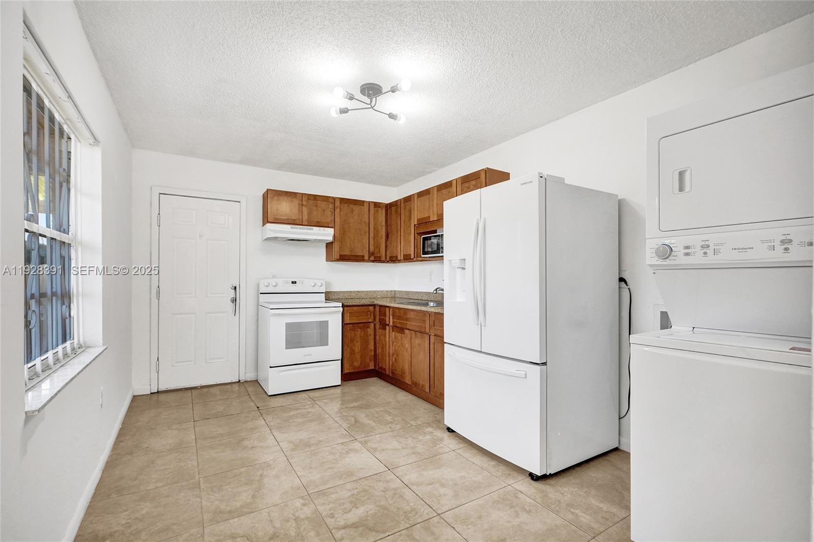 2907 Northwest 103rd Street, Unit 1 Miami, FL 33147 - Photo 11 of 38 a kitchen with a refrigerator a stove top oven and cabinets