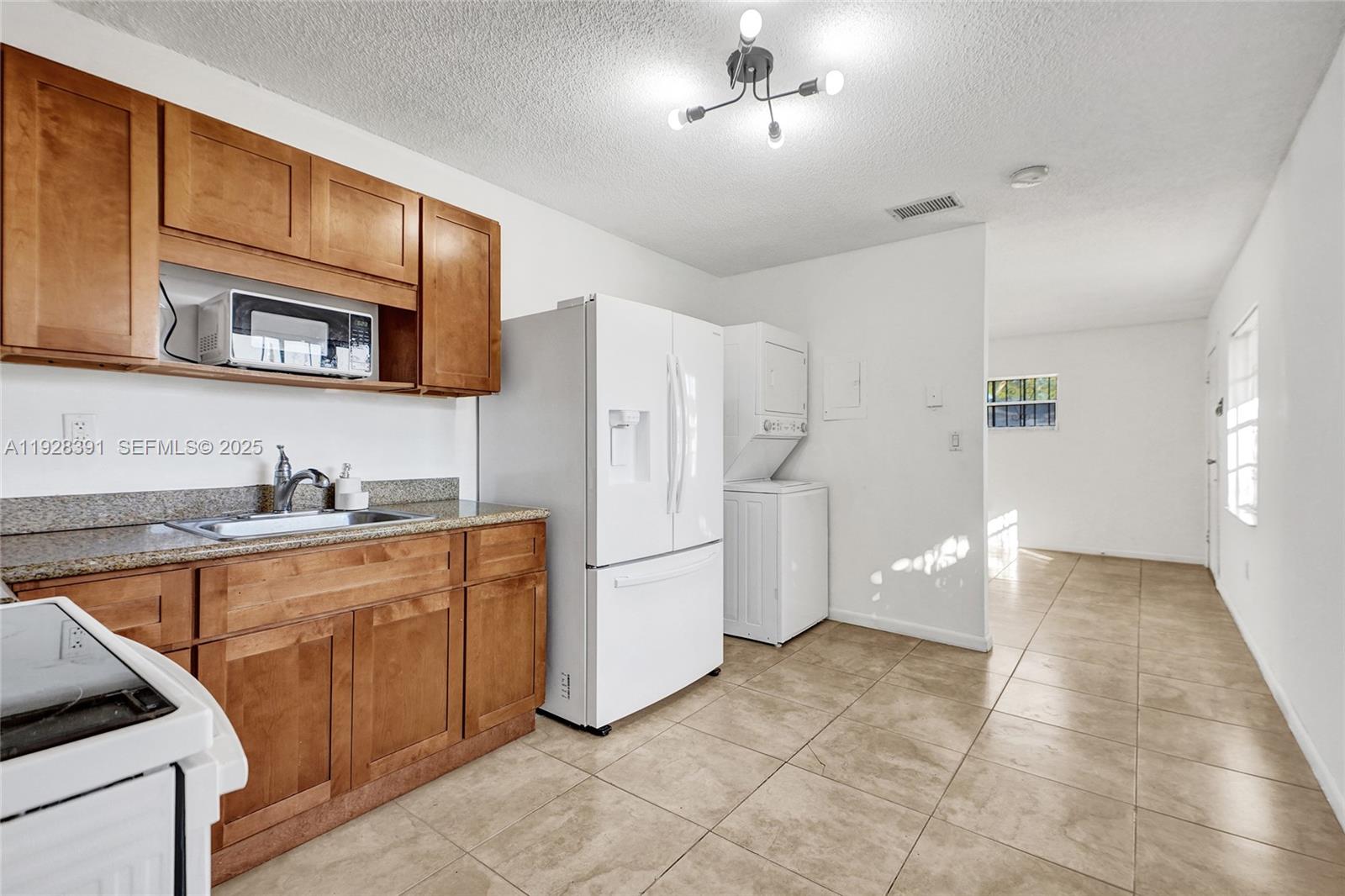 2907 Northwest 103rd Street, Unit 1 Miami, FL 33147 - Photo 12 of 38 a kitchen with stainless steel appliances granite countertop a refrigerator and a stove top oven
